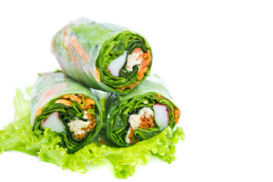 Three vegetable spring rolls stacked on a bed of lettuce.