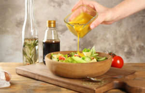 A woman pours homemade salad dressing over her salad.