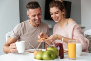 A couple eats a healthy breakfast with juice and coffee.