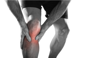 A runner grabs his knee in pain.