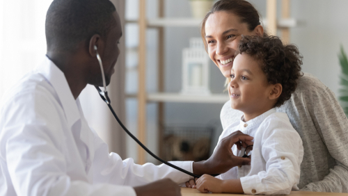 A primary care physician exams a child while its mother looks on.
